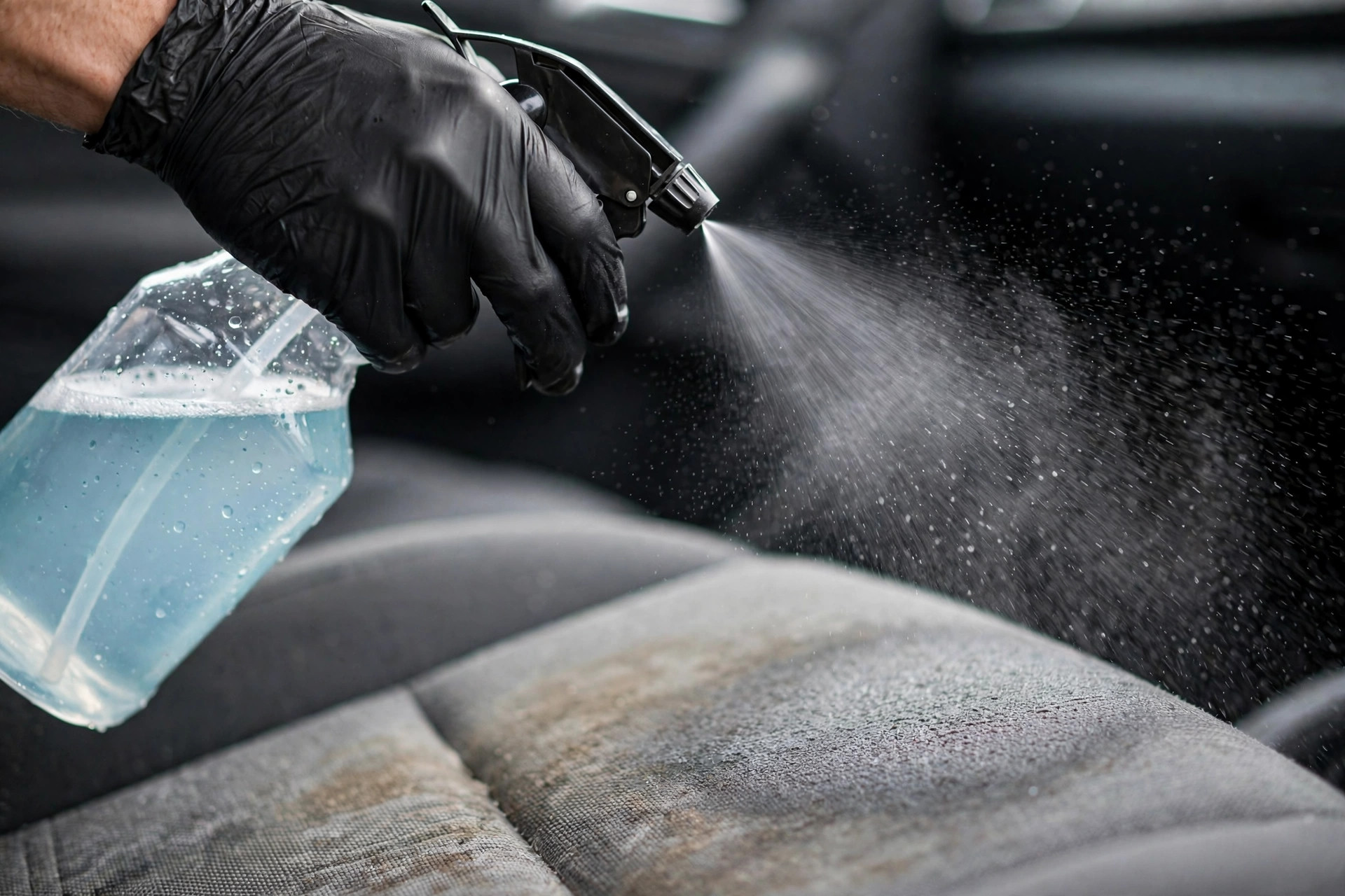 Pre-treatment cleaner being sprayed on a stained car seat